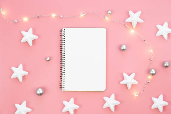 Blank notebook with stars, garland are scattered next to the notebook. Place for a wish list, gifts or goals for the year.