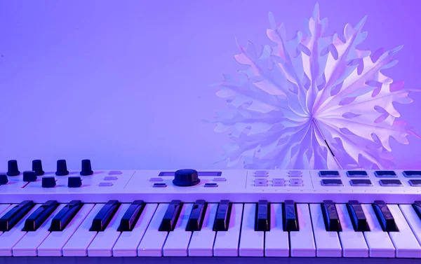 Minimalistic Christmas background with midi keyboard, paper snowflake with neon lighting, copy space.