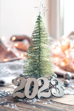 2023 numaralı Noel kompozisyonu ve bulanık bir arka planda dekoratif bir Noel ağacı..