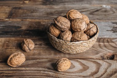 Yakın plan, ahşap bir arka planda hasır bir kasede ceviz, kırsal stil, kopyalama alanı.