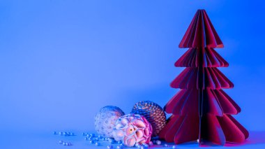 Minimalist yaratıcı Noel ve yeni yıl sanat kompozisyonu. Mavi arka planda noel topları olan köknar ağacı ve modaya uygun neon ışığı. Boşluğu kopyala, metin için boşluk.
