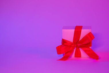 Neon ışıklı kırmızı fiyonklu hediye kutusu izole edildi, kopyalama alanı.