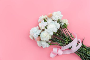 Pembe arka planda beyaz karanfillerden oluşan bir buket izole, düz, kopyalama alanı.