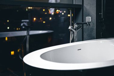 Gece şehrine bakan penceresi olan modern bir tuvaletin içini kopyalayın..