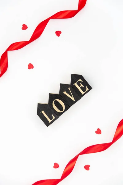 Decorative word love and red ribbons on a white background isolated, flat lay.