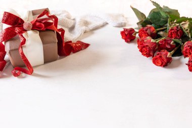 Bir hediye kutusu ve beyaz arka planda bir buket kırmızı gül ile şenlikli arka plan, kopyalama alanı.