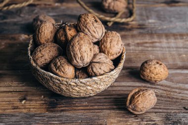 Yakın plan, ahşap bir arka planda hasır bir kasede ceviz, kırsal stil, kopyalama alanı.