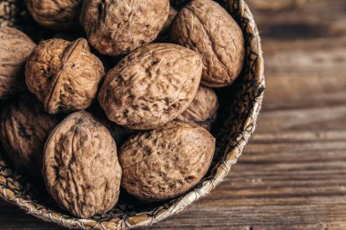 Yakın plan, ahşap bir arka planda hasır bir kasede ceviz..