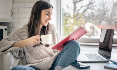Elinde not defteri ve sabah mutfakta bir fincan kahveyle iş kadını..