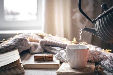 Bir çaydanlık ve bir fincan ile rahat ev kompozisyonu, hareket halindeki çayı dökme süreci, boşluğu kopyalama.