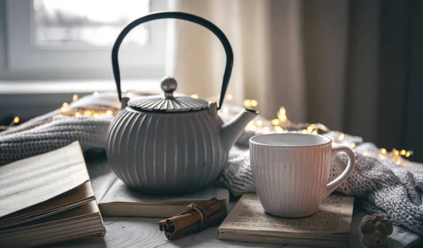 Cozy home composition with textured gray teapot, cup and book on blurred background, copy space.
