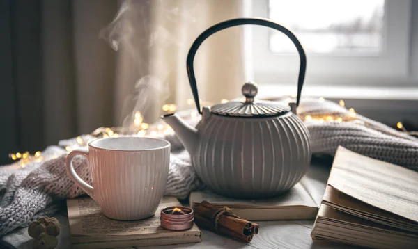 Cozy home composition with textured gray teapot, cup and book on blurred background, copy space.