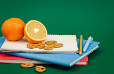 Yeşil arka planda notlar ve turuncu, okul atıştırmalığı konsepti, kopyalama alanı.