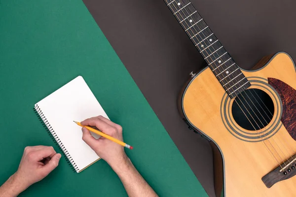 Flat lay, acoustic guitar and notebook on color background, copy space.