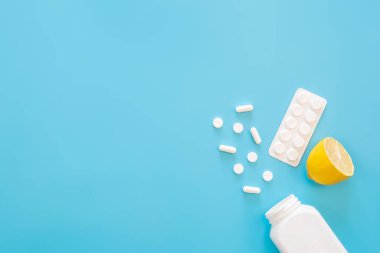 Pills and lemon on a blue background, flat lay, copy space, medicine and treatment concept.