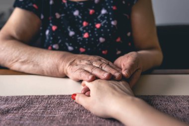 Yaşlı ve genç kadınların el ele tutuşması, yaşlı bakımı ve saygısı, yakın çekim.