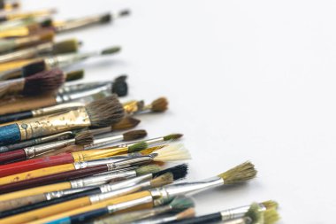 Close-up of paint brushes dirty from paints on a white background.