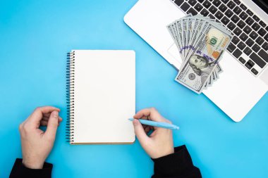 Erkek eller, boş not defteri ve dizüstü bilgisayarda para, düz döşeme, kopyalama alanı.