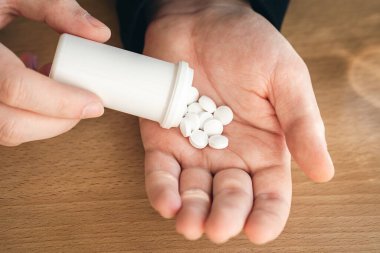 A lot of white pills in the hands of an adult man, close up.