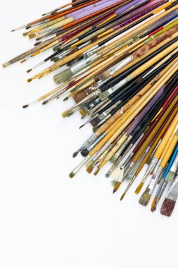 Many brushes for drawing in paint on a white background, top view, copy space.
