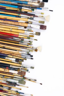 Many brushes for drawing in paint on a white background, top view, copy space.