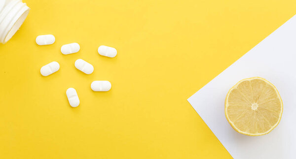Таблетки и лимон на желтом фоне, плоский узор, концепция витамина С.