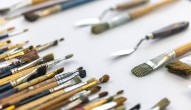 Paint brushes stained with paint on a white background, macro shot, soft focus, drawing and art concept.