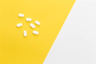 Pills on a yellow background, conceptual minimalism, copy space.