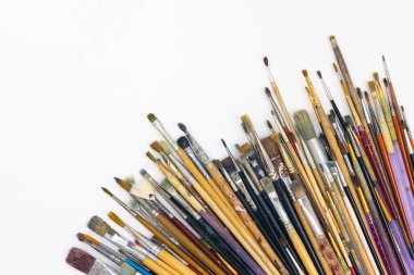 Many brushes for drawing in paint on a white background, top view, copy space.