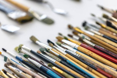 Paint brushes stained with paint on a white background, macro shot, soft focus, drawing and art concept.