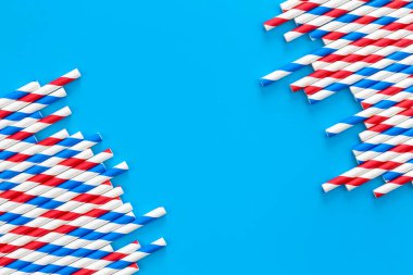 Drinking straws for party on blue background with copy space. Top view of colorful paper disposable eco-friendly straws for summer cocktails.