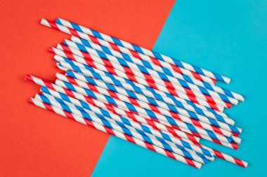 Drinking straws for party on colored background, copy space. Top view of colorful paper disposable eco-friendly straws for summer cocktails.
