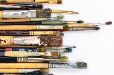 Close-up of paint brushes dirty from paints on a white background.
