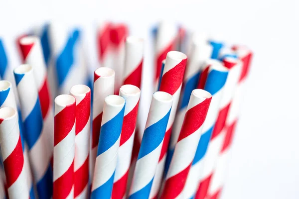 Multi-colored paper straws for drinks close-up on a white background, macro shot.