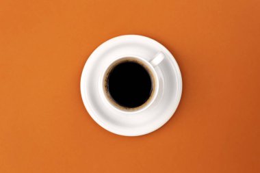 Coffee cup and saucer on brown background, flat lay, conceptual minimalism.