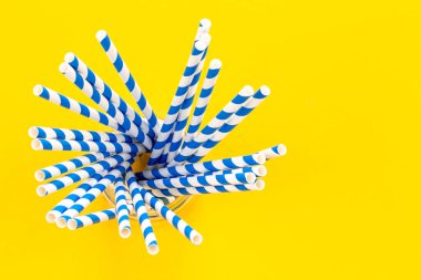 Striped vintage paper straws for drinks on a yellow background, top view.