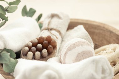 Spa composition with soap, bath bomb and towels in a wooden bowl on a blurred background.