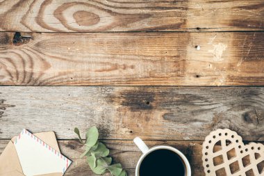 Wooden vintage background with a letter, a cup of coffee and a wooden heart camera.