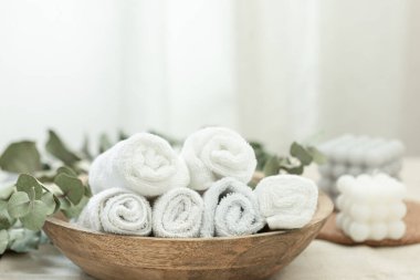 Spa composition with white towels in a wooden plate, copy space.