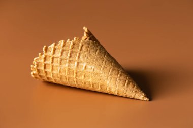Textured waffle cone on a brown background isolated, for dessert and ice cream. Creative macro concept of sweets and food.
