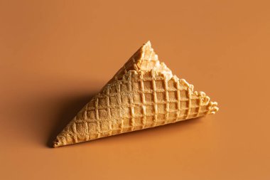 Textured waffle cone on a brown background isolated, for dessert and ice cream. Creative macro concept of sweets and food.