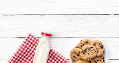Bottle of milk and cookies on a wooden background, top view, rustic style, copy space.