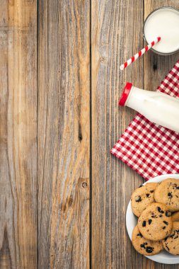 Milk and cookies with chocolate on a wooden background, flat lay, copy space.
