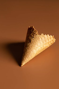 Textured waffle cone on a brown background isolated, for dessert and ice cream. Creative macro concept of sweets and food.