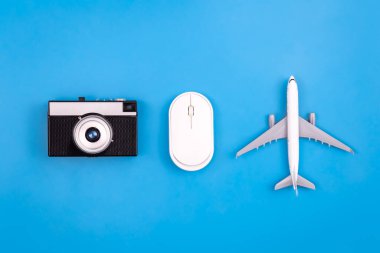 Vintage camera, computer mouse and airplane miniature on a blue background, flat lay.