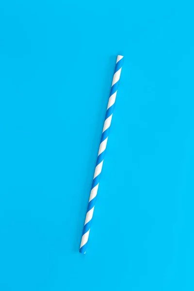Close up of drinking straw for party, blue spiral. Top view of colorful disposable eco-friendly straw for summer cocktails. Paper cocktail colorful straw isolated on blue background, isolated.