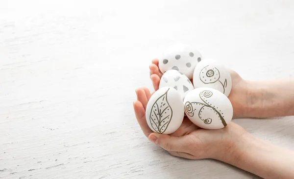 Easter eggs, hand-painted, in childrens hands on a white background, copy space.