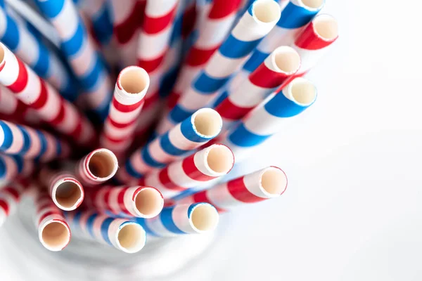 Multi-colored paper straws for drinks close-up on a white background, top view.