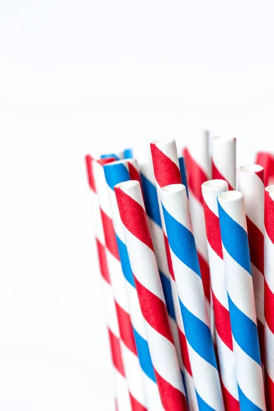Multicolored paper straws for drinks at a party in a glass jar, close-up on a white background.