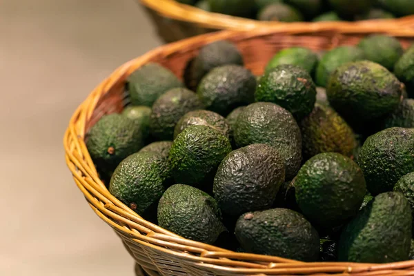 Avocados in basket for sale at fruit stall, close up.